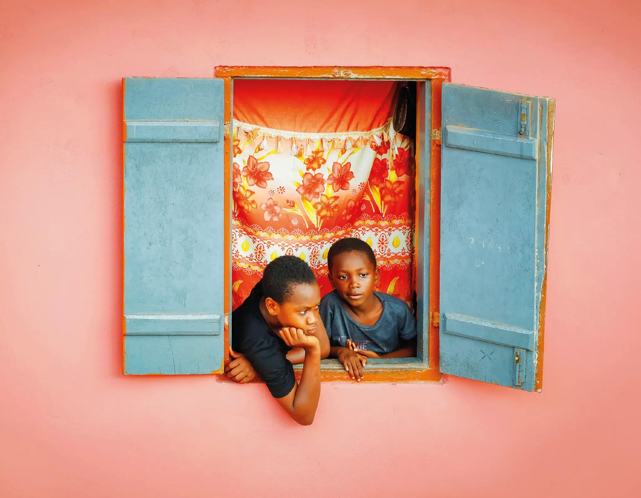Two young girls watch the vibrant durbar procession from their home window